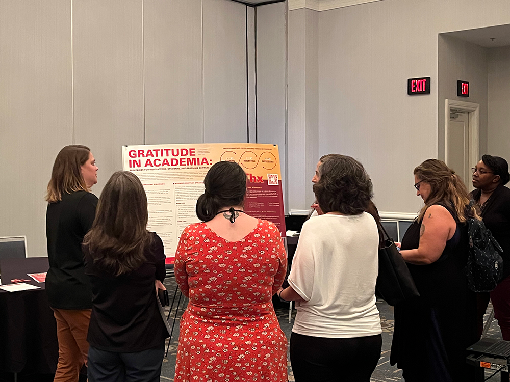 Faculty, staff, and teachers gather in front of a poster during the 2023 Sunshine Teaching and Learning Conference in Orlando in May of 2023.